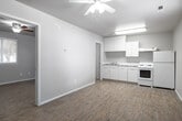 This single-story unit at 7529 W Florence Ln in Boise, Idaho, offers a clean, straightforward layout designed for practical living. Light wood-style flooring runs consistently throughout the space, contributing to a bright and cohesive feel across all rooms.

The open living and kitchen area forms the heart of the unit. The kitchen is equipped with white cabinetry, a single-basin sink, light marble-patterned countertops, a white electric coil range with overhead ventilation hood, and a full-size refrigerator. A ceiling fan overhead provides air circulation to the combined living and kitchen space. The neutral white walls and light flooring keep the area feeling open and airy.

Adjacent rooms offer flexible living spaces, each featuring the same wood-style flooring and neutral wall tones. One room includes a window fitted with white horizontal blinds, allowing natural light to filter in while maintaining privacy. Another room features attic access panels in the ceiling, adding a practical utility element.

The bathroom is efficiently laid out, including a tub and shower combination with a curved curtain rod, a vanity with a marble-patterned countertop, and a small window above the tub for natural light and ventilation. The overall design of the space is clean, functional, and move-in ready.