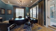 This single-floor professional office space presents a cohesive and polished aesthetic throughout, defined by deep teal walls, crisp white crown molding, and warm tile flooring. The executive office is a standout area, anchored by a large dark desk and complemented by leather seating, a vibrant abstract area rug, and a striking sputnik-style chandelier overhead. Multiple windows dressed with wooden blinds and plaid drape panels fill the room with natural light while offering views of the surrounding exterior. A reception and transitional hallway area connects the spaces seamlessly, featuring a dark console cabinet topped with decorative lamps and framed artwork adorning the walls. This welcoming entry zone provides a professional first impression with ample wall-mounted controls and display elements. Adjacent to the main office, a casual meeting nook offers round bistro-style tables and chairs, ideal for informal gatherings or client consultations. The same sputnik chandelier motif continues here, reinforcing design continuity. Natural light pours in through generously sized windows, and the bold area rug ties the color palette together throughout. The overall ambiance is both functional and visually engaging, blending contemporary design elements with a warm, inviting atmosphere suited for a professional office environment.