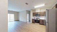 This well-appointed one-bedroom, one-bathroom residence at Fort George G. Meade, Maryland offers a thoughtfully designed single-floor layout. The open-concept living and kitchen area is anchored by warm light wood-style flooring that extends throughout, creating a cohesive and inviting atmosphere. The kitchen is fully equipped with a complete suite of stainless steel appliances, including a refrigerator, range, built-in microwave, and dishwasher. Rich dark brown cabinetry paired with white tile backsplash and light countertops provides ample storage and a clean, modern aesthetic. A sliding glass door in the living area opens to a private balcony, allowing natural light to flow in and offering an outdoor retreat. The bedroom is carpeted for added comfort and features a large window that brings in additional natural light, along with a double-door closet providing generous storage space. The bathroom is finished with a wood-vanity cabinet, white countertop, and well-lit mirror above the sink, complemented by tile flooring. Clean neutral tones throughout the residence create a bright, move-in-ready environment suitable for comfortable everyday living.