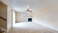 This two-story home in Round Rock, Texas offers a well-organized layout spread across two floors. The main level welcomes you through an entrance that flows into a combined kitchen and living room. The living room is a comfortable, carpeted space anchored by a tile-surround fireplace with a classic mantle and equipped with a ceiling fan with light kit, creating a warm, inviting atmosphere. Natural light filters in through windows fitted with horizontal blinds. The kitchen features dark cabinetry, a white electric range, refrigerator, and tile flooring. A pass-through countertop bar connects the kitchen to the living area, enhancing the open feel of the main floor. A half bathroom is also conveniently located on this level. Upstairs, two carpeted bedrooms offer comfortable retreats. The spacious primary bedroom includes a ceiling fan, a large window, and access to a walk-in closet with built-in shelving. The second bedroom features generous sliding door access with vertical blinds, allowing ample natural light. Three bathrooms in total are distributed throughout the home, each featuring tile flooring, dark vanity cabinetry, and light stone countertops. A staircase and hallway connect the two floors, completing this functional and cozy home.