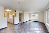 Located at 4740 21st Ave NE in Seattle's University District, this 2-bedroom, 1-bathroom unit offers a practical and well-organized layout across a single floor. The open-concept living and dining area is bright and inviting, featuring wood-look laminate flooring and large windows that frame lush Pacific Northwest greenery, filling the space with natural light. The kitchen is positioned adjacent to the living area and includes light wood cabinetry, a full-size refrigerator, electric range, and a dishwasher, making it both functional and accessible. A hallway connects the main living areas to the private quarters, where both bedrooms are carpeted for comfort. The primary bedroom offers a generous footprint with a sliding-door closet and a window overlooking the surrounding trees. The second bedroom also features carpet, a closet, and access to natural light. The shared full bathroom includes a soaking tub with tiled surround walls. Additional highlights include an in-unit laundry area and ample closet storage throughout. The neutral color palette and clean finishes give the space a move-in-ready feel suited for a variety of living arrangements.