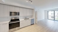 Located on the fifth floor at 103 W Camino Real in the heart of Boca Raton, FL, this contemporary apartment offers 2 bedrooms and 3 bathrooms across a well-designed single-level layout. Light wood-style flooring flows throughout, creating a bright and cohesive aesthetic complemented by crisp white walls and clean-lined architecture.

The modern kitchen is outfitted with stainless steel appliances — including a French door refrigerator, electric range, microwave, and dishwasher — alongside sleek two-tone cabinetry, light countertops, and track lighting overhead. It opens seamlessly into the living area, enhancing the sense of openness.

Both bedrooms are generously proportioned, with large windows fitted with blinds that invite natural light and offer views of the surrounding neighborhood. The spacious primary bedroom includes access to a dedicated closet with built-in wire shelving for organized storage.

The three bathrooms are finished to a high standard, featuring large-format tile work. One bathroom includes a full soaking tub with a tiled surround, while another showcases a walk-in glass-enclosed shower. All bathrooms feature clean white vanities and modern fixtures.

A hallway connects the private areas of the home, and two closets provide ample storage throughout. The overall ambiance is modern, airy, and move-in ready.