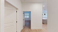 Located at Stadium Way in Madison, Alabama, this thoughtfully designed single-floor residence offers a clean, contemporary aesthetic throughout. Light wood-tone flooring flows seamlessly across all areas, creating a cohesive and bright interior palette anchored by crisp white walls and trim.

The open-concept living area is generously proportioned, featuring a ceiling fan, large French doors with transom windows, and flanking sidelights that invite abundant natural light. The kitchen is well-equipped with white shaker cabinetry, stainless steel appliances including a refrigerator, microwave, and range, a textured tile backsplash, and a large island with a undermount sink and brushed gold faucet, illuminated by striking black pendant lights.

The bedrooms are comfortably sized with natural light provided by blinded windows. The primary bedroom connects to an en-suite bathroom featuring a dual-sink vanity with light countertops, gray accent walls, and a glass-enclosed walk-in shower with brushed gold fixtures. A second full bathroom offers a tub-shower combo, vanity with mirror, and matching finishes. A hallway with black-hardware doors connects the private areas of the unit, with additional storage and a walk-in closet visible from the primary bedroom.