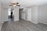 Located on Woodrow Bean Transmountain Drive in El Paso, Texas, this two-story home offers a clean, updated interior with a consistent neutral color palette throughout. Light wood-style flooring runs through the living areas and bedrooms, complementing the soft gray walls and white baseboards to create a bright, cohesive aesthetic.

The kitchen is well-appointed with gray cabinetry featuring modern hardware, white countertops, a subway tile backsplash, and black appliances including a refrigerator and dishwasher. A window above the sink allows natural light to fill the space. The bathroom includes a full tub-shower combination with chrome fixtures, a toilet, and a vanity with wood-style flooring extending throughout.

Multiple rooms across both floors are generously proportioned, each featuring ceiling fans with integrated lighting, horizontal window blinds that allow natural light, and textured ceilings. A staircase with wooden treads and white railings connects the two levels, as visible in the architectural overview. The overall ambiance is clean, functional, and move-in ready, with a neutral design that suits a variety of furnishing styles.