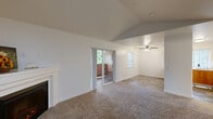 Located at 2501 NE 138th Ave in Vancouver, Washington, this single-floor, three-bedroom, two-bathroom home offers a well-organized layout with a variety of functional spaces. The living room is a standout feature, boasting vaulted ceilings and a classic white-mantled fireplace, creating an open and inviting atmosphere. Sliding glass doors lead directly to a private balcony with views of surrounding greenery, allowing natural light to fill the space. The combined dining room and kitchen area features warm oak cabinetry with ample storage, light countertops, wood-look vinyl flooring, and white appliances including a dishwasher, range, and refrigerator. A ceiling fan with a window view adds comfort to the dining area. The three carpeted bedrooms are well-proportioned, each with natural light from windows framed by vertical blinds. Four closets are distributed throughout the home, providing generous storage. Both bathrooms are finished with wood-look flooring and vanity cabinetry. Additional amenities include a dedicated laundry area, pantry, and a hallway connecting the private quarters. A pet door is also present, adding a practical touch for pet owners.