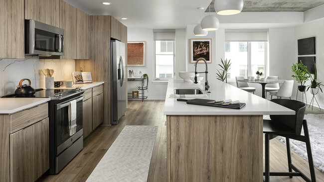 Cocina del apartamento con electrodomésticos de acero inoxidable, comedor y suelos de madera. - Griffis LoDo