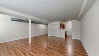 Located at 901 Draper Ave in Schenectady, NY, this single-floor unit offers a practical and well-organized layout designed for comfortable everyday living. Rich hardwood-style flooring runs throughout the space, lending warmth and continuity across every room.

The open-concept living area is generously proportioned, featuring neutral beige walls, exposed support columns, and visible ductwork that lend the space an industrial character. Windows along the exterior wall allow natural light to fill the room, creating a bright and airy atmosphere.

The kitchen is efficiently arranged with rich wood cabinetry, light countertops, a stainless steel refrigerator, and a built-in range. A peninsula with a sink provides additional prep space and a natural transition between the kitchen and the living area.

A long hallway connects the main living spaces to the private areas of the unit, including a full bathroom and a closet. The bathroom is finished with stone-tile flooring and includes a full tub and shower combination with brushed nickel fixtures, complemented by neutral walls for a clean, timeless look.

The closet offers dedicated storage space, contributing to the unit's overall functionality. The consistent use of neutral tones and quality finishes throughout creates a cohesive, move-in-ready environment.