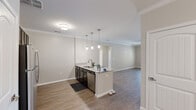 This single-story home in Round Rock, Texas offers a well-designed layout with four bedrooms and two bathrooms. The open-concept living area seamlessly connects the kitchen, dining, and living spaces, creating a bright and functional hub for daily life. The kitchen is a standout feature, boasting dark cabinetry, granite countertops, stainless steel appliances, and a peninsula island with pendant lighting overhead — ideal for both cooking and casual dining. Crown molding throughout the main living areas adds a refined architectural touch.

The dining area is appointed with a brushed nickel chandelier, complementing the neutral palette that flows consistently through the home. Wood-style hard flooring runs through the main living spaces, while select bedrooms feature plush carpeting for added comfort. Each bedroom offers natural light through blinded windows, and ceiling fans are present in several rooms for climate comfort. The bathrooms are finished with tile flooring and clean, simple fixtures.

A dedicated hallway connects the private bedroom wing, and a closet provides additional storage. The overall design emphasizes a neutral, move-in-ready aesthetic with modern finishes, making this home a practical and comfortable residence in the Round Rock, TX area.