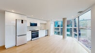 Located on Queen Street in the heart of Halifax, this modern unit offers a thoughtfully designed open-concept layout with clean lines and contemporary finishes throughout. Light hardwood flooring runs continuously through the living spaces, complementing the bright, neutral palette.

The kitchen and living area form a seamless open space, with the kitchen showcasing sleek white cabinetry, a marble-style tile backsplash, stainless steel appliances including a Whirlpool range and built-in microwave, and a undermount sink with modern fixtures. A dramatic exposed concrete column anchors the living area, adding an industrial design element, while floor-to-ceiling windows frame views of the surrounding Halifax streetscape and fill the space with natural light.

The bedroom is generously sized and features a built-in closet with shelving, recessed lighting, and the same warm hardwood flooring. Two full bathrooms serve the unit — one features a frameless glass sliding shower enclosure with tile surround, while the second includes a soaking tub with full-height tile walls. Additional storage is provided through multiple closets, and in-unit stacked laundry is conveniently included. A balcony offers open views of the vibrant urban neighborhood below.