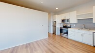 Located at 2615 E 29th St in Minneapolis, MN, this efficiently designed one-bedroom, one-bathroom unit offers a clean, contemporary aesthetic across a single floor. Light wood-style flooring runs throughout, complementing the bright white walls and recessed lighting that keep the space feeling open and airy.

The combined kitchen and living area serves as the heart of the unit. The kitchen is outfitted with stainless steel appliances—including a range, microwave, refrigerator, and dishwasher—paired with white cabinetry, light countertops, and a subtle gray subway tile backsplash. The open layout allows the living area to flow naturally from the kitchen.

The bedroom is a comfortable, private retreat featuring large floor-to-ceiling windows with bold black frames that invite abundant natural light and offer open views of the surrounding Minneapolis neighborhood. A wall-mounted HVAC unit ensures year-round climate control.

The bathroom maintains the unit's clean design language with wood-style flooring, a white vanity with ample storage, a full soaking tub with shower, and a large mirror. A dedicated closet and in-unit laundry add practical convenience. A long hallway with recessed lighting connects the rooms, reinforcing the unit's modern, streamlined character.
