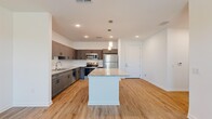 Located at 1191 W Price Blvd in North Port, Florida, this well-appointed 2-bedroom, 2-bathroom residence offers a thoughtfully designed single-floor layout with modern finishes throughout. The open-concept kitchen serves as the heart of the home, showcasing a large granite-topped center island with pendant lighting, gray shaker-style cabinetry, a white subway tile backsplash, and a full suite of stainless steel appliances including a refrigerator, range, microwave, and dishwasher. Light wood-tone flooring flows seamlessly from the kitchen into the adjacent living area, which is brightened by recessed lighting and a ceiling fan. Both bedrooms are bright and comfortable, featuring the same warm flooring, ceiling fans, and windows that invite natural light. The primary bedroom includes a spacious closet with paneled bi-fold doors. The two bathrooms are finished with matching gray cabinetry, granite countertops, tile flooring, and large mirrors with overhead lighting. One bathroom features accessibility grab bars, adding practical versatility. Clean white walls and crisp trim throughout lend the space a fresh, contemporary feel.