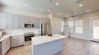 Located at 760 W Bedford Euless Rd in Hurst, TX, this well-designed single-story home offers a thoughtful layout with one bedroom and two full bathrooms across a compact yet functional footprint. The open-concept kitchen serves as the centerpiece of the home, showcasing gray shaker-style cabinetry, a large white waterfall island, stainless steel appliances including a French door refrigerator, range, microwave, and dishwasher, complemented by a subway tile backsplash. Light wood-look luxury vinyl plank flooring runs throughout the main living areas, enhancing the bright, airy atmosphere created by recessed lighting and natural light from multiple windows. The bedroom features soft carpet flooring, a ceiling fan, and a closet, with direct access to a secondary bathroom fitted with blue cabinetry. The primary bathroom is finished with granite countertops, gray vanity cabinetry, large-format tile flooring, and a glass-enclosed walk-in shower with floor-to-ceiling tile surround. Neutral tones, clean lines, and modern fixtures create a cohesive and contemporary aesthetic throughout the entire home.