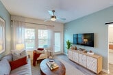 Located in Jacksonville, FL, this single-floor, 2-bedroom, 2-bathroom residence offers a thoughtfully designed layout with modern finishes throughout. The open-concept living room features light wood-style flooring, a ceiling fan, and large windows that invite abundant natural light. A soft sage-green accent wall anchors the space, complemented by sheer curtains and direct access to an outdoor area. The kitchen is equipped with stainless steel appliances, two-tone cabinetry in white and gray, and recessed lighting. A dining area adjacent to the kitchen comfortably accommodates a round table and chairs. The spacious primary bedroom features a bold teal accent wall, a ceiling fan, and a walk-in closet with wire shelving for ample storage. The second bedroom offers a ceiling fan, natural light from a window, and its own closet. Both bathrooms are finished in a coordinating sage palette, with one featuring a full shower-tub combination. A dedicated laundry room houses a full-size washer and dryer, accessed through a louvered door. Hardwood-style flooring runs throughout the home, tying together the clean, contemporary aesthetic of this well-organized Jacksonville residence.