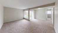 This renovated two-bedroom, one-bathroom unit at The Gallup offers a well-organized single-floor layout designed for comfortable everyday living. The spacious living area is finished with plush carpeting and neutral-toned walls, creating a bright and welcoming atmosphere. A large picture window alongside a sliding glass door fills the room with natural light while providing direct views of the surrounding greenery and outdoor space beyond.

The kitchen has been thoughtfully updated with white shaker-style cabinetry, granite countertops, a stainless steel double-basin sink, and a stainless steel dishwasher. Wood-look flooring ties the space together, offering both durability and visual appeal. The layout provides ample counter and storage space for practical use.

Both bedrooms are carpeted and feature built-in closets with bifold doors, shelving, and hanging rods for organized storage. One bedroom includes a tall narrow window that introduces additional natural light. The shared full bathroom continues the renovated aesthetic with a granite-topped vanity, white cabinetry, a framed mirror, and a tub-shower combination, all finished with wood-look flooring. The overall design presents a clean, cohesive, and move-in-ready environment.