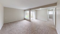 This renovated two-bedroom, one-bathroom unit at The Gallup offers a well-organized single-floor layout designed for comfortable everyday living. The spacious living area is finished with plush carpeting and neutral-toned walls, creating a bright and welcoming atmosphere. A large picture window alongside a sliding glass door fills the room with natural light while providing direct views of the surrounding greenery and outdoor space beyond.

The kitchen has been thoughtfully updated with white shaker-style cabinetry, granite countertops, a stainless steel double-basin sink, and a stainless steel dishwasher. Wood-look flooring ties the space together, offering both durability and visual appeal. The layout provides ample counter and storage space for practical use.

Both bedrooms are carpeted and feature built-in closets with bifold doors, shelving, and hanging rods for organized storage. One bedroom includes a tall narrow window that introduces additional natural light. The shared full bathroom continues the renovated aesthetic with a granite-topped vanity, white cabinetry, a framed mirror, and a tub-shower combination, all finished with wood-look flooring. The overall design presents a clean, cohesive, and move-in-ready environment.