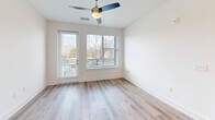 Located at 523 N Spring St in Greensboro, NC, this well-appointed one-bedroom, one-bathroom residence offers a thoughtfully designed open-concept floor plan that maximizes its comfortable footprint. Light wood-tone flooring flows throughout, complemented by crisp white walls and abundant natural light streaming through multiple windows fitted with blinds.

The combined dining, kitchen, and living area serves as the heart of the home. The kitchen stands out with white shaker-style cabinetry, light blue subway tile backsplash, white quartz countertops, stainless steel appliances, and a large center island with a built-in sink illuminated by pendant lighting overhead. A pantry provides additional storage convenience.

The bedroom is bright and spacious, featuring a ceiling fan, large windows with outdoor views, and a dedicated closet. The bathroom is elegantly finished with white cabinetry, a quartz vanity, and a glass-enclosed walk-in shower adorned with large-format marble-style tile and brushed nickel fixtures.

Additional highlights include a private balcony accessible from the living area, an in-unit laundry space, and a ceiling fan in the main living area. The overall aesthetic is clean, modern, and move-in ready.