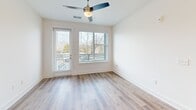 Located at 523 N Spring St in Greensboro, NC, this well-appointed one-bedroom, one-bathroom residence offers a thoughtfully designed open-concept floor plan that maximizes its comfortable footprint. Light wood-tone flooring flows throughout, complemented by crisp white walls and abundant natural light streaming through multiple windows fitted with blinds.

The combined dining, kitchen, and living area serves as the heart of the home. The kitchen stands out with white shaker-style cabinetry, light blue subway tile backsplash, white quartz countertops, stainless steel appliances, and a large center island with a built-in sink illuminated by pendant lighting overhead. A pantry provides additional storage convenience.

The bedroom is bright and spacious, featuring a ceiling fan, large windows with outdoor views, and a dedicated closet. The bathroom is elegantly finished with white cabinetry, a quartz vanity, and a glass-enclosed walk-in shower adorned with large-format marble-style tile and brushed nickel fixtures.

Additional highlights include a private balcony accessible from the living area, an in-unit laundry space, and a ceiling fan in the main living area. The overall aesthetic is clean, modern, and move-in ready.