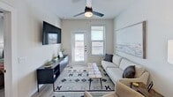 This 490 square foot, one-bedroom apartment offers a blend of modern design and practical living. The kitchen is a standout feature, boasting dark wood cabinetry, stainless steel appliances, and granite countertops. It's equipped with a full-size refrigerator, built-in microwave, and electric range, ideal for preparing meals.

The living area is open and airy, with light wood flooring that extends throughout the apartment. A ceiling fan with integrated lighting adds both style and comfort. The space is versatile, accommodating a sitting area with a couch and armchair, as well as a small dining table.

The bedroom, measuring 130 square feet, features a large window for natural light and is furnished with a comfortable bed and side tables. The bathroom is modern and sleek, with a granite-topped vanity, large mirror, and a shower/tub combination.

Throughout the apartment, neutral tones dominate, creating a calm and inviting atmosphere. Thoughtful touches like coastal-themed artwork and decorative elements add character. The apartment also includes a closet for storage and a separate entrance, enhancing its functionality and privacy.
