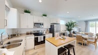 Located at 43738 Buena Vista Way in Lancaster, CA, this single-story 2-bedroom, 2-bathroom home offers a thoughtfully designed layout with a clean, contemporary aesthetic throughout. Light-toned hardwood-style flooring flows seamlessly across the living spaces, complementing the bright white walls and recessed lighting that give the home an airy, welcoming feel.

The kitchen is a standout feature, boasting crisp white cabinetry, stainless steel appliances including a dishwasher, electric range, microwave, and refrigerator, as well as a central island with a butcher block top and bar seating — ideal for casual dining or entertaining. Natural light filters in through a window above the sink, enhancing the clean, open atmosphere.

The living room is a comfortable retreat with ample space for seating and décor, while the adjacent dining area provides a seamless flow for everyday living. Three closets offer generous storage throughout the home.

The primary bedroom includes a dedicated closet, while the two bathrooms are finished in a bright, minimalist style — one featuring a glass-enclosed walk-in shower and the other a full soaking tub with subway tile surround. A dedicated laundry area adds everyday convenience.

A dollhouse view reveals a landscaped outdoor area with a patch of lawn, extending the living space beyond the home's interior.
