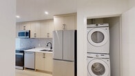 Located at 2318 15 St SW in Calgary's desirable inner-city neighbourhood, this thoughtfully designed 2-bedroom, 1-bathroom unit offers a modern aesthetic with high-quality finishes throughout. The galley-style kitchen is a standout feature, showcasing light wood cabinetry with matte black hardware, white quartz countertops, a mosaic tile backsplash, and a full suite of stainless steel appliances including a French door refrigerator, electric range, built-in microwave, and dishwasher. A stacked Samsung washer and dryer is conveniently tucked adjacent to the kitchen. Light-toned hardwood flooring flows throughout the unit, complementing the clean, neutral colour palette. The two bedrooms are bright and minimalist, each featuring baseboard heating and light wood floors. The primary bedroom includes a window with views to the surrounding neighbourhood and green trees. The full bathroom is elegantly appointed with large-format tile, a modern floating vanity with white countertop, matte black fixtures, and a glass sliding door enclosing a deep soaker tub and shower combo. A connecting hallway provides smooth flow between all rooms, making efficient use of the overall footprint while maintaining a clean, contemporary feel throughout.