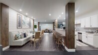 Located at 4460 Mountain Laurel Rd in Hilliard, Ohio, this thoughtfully designed single-floor amenity space offers a sophisticated and welcoming environment that seamlessly blends comfort with modern elegance. The open-concept layout flows effortlessly between distinct functional zones, all unified by large-format dark tile flooring, crisp white walls, and warm wood accent columns that add natural texture throughout.

The lounge area features plush, neutral-toned seating with decorative throw pillows and curated artwork, creating an inviting space for relaxation or casual conversation. Adjacent to the lounge, a dedicated dining area draws the eye with a striking patterned accent wall, a bold turquoise globe pendant chandelier, and a sleek dark dining table surrounded by upholstered chairs. A living wall of lush greenery adds a refreshing natural element nearby.

The bar and kitchenette area is well-appointed with white shaker cabinetry, a beverage station, bar-height seating along a counter peninsula, and modern appliances including a dishwasher. A wall-mounted television and a pool table are visible in an adjoining recreation zone, adding entertainment options. A secondary lounge nook features wingback chairs, woven basket wall décor, a mounted television, and bold double doors — providing a quieter retreat within the larger space.
