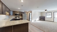 This single-floor unit is designed with a practical, open-concept layout that connects the kitchen and living area seamlessly. The kitchen is well-appointed with dark-toned shaker-style cabinetry, light granite-look countertops, and a full suite of stainless steel appliances, including a range, microwave, dishwasher, and refrigerator. A central island provides additional prep and seating space, while light wood-look flooring grounds the area with a clean, modern feel. The adjoining living space transitions to plush carpeting and features a corner fireplace, adding a warm focal point to the room.

The bedrooms are carpeted and offer a comfortable, quiet atmosphere. Each room includes a ceiling fan, a window for natural light, and closet storage. The neutral wall tones and dark trim detailing create a cohesive aesthetic throughout.

Two bathrooms serve the unit. One includes a vanity with granite-look counters, a soaking tub, and a stacked Samsung washer and dryer conveniently integrated into the space. The second bathroom features a walk-in shower, a matching vanity, and light wood-look flooring. Overall, the unit offers a functional, well-finished living environment with consistent design details throughout.
