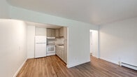 Located at 207 Water Street in Brooklyn, Michigan, this one-bedroom, one-bathroom unit offers a practical and efficiently designed single-floor layout. The living room is bright and welcoming, featuring durable hardwood-style flooring, a baseboard heating system, and a sliding glass door that fills the space with natural light while providing a pleasant view of the surrounding greenery. A wall-mounted AC unit adds year-round climate control comfort.

The kitchen is neatly integrated into the living area via an open pass-through design, showcasing taupe cabinetry with panel-style doors, marble-patterned countertops, a double stainless steel sink, and white appliances including a refrigerator and electric range. Upper and lower cabinetry provide ample storage.

A hallway connects the main living area to the private spaces, leading to the carpeted bedroom, which offers a comfortable footprint, a window for natural light, baseboard heating, and direct access to a dedicated closet. The full bathroom is clean and functional, featuring a white tub-shower combination with a surround enclosure. Throughout the unit, crisp white walls and clean finishes contribute to a neutral, move-in-ready aesthetic.