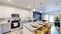 Located at 1300 S Davis Rd in LaGrange, Georgia, this well-appointed one-bedroom, one-bathroom residence offers a smart, efficient layout across a single floor. The open-concept kitchen and living area serves as the heart of the home, anchored by a granite-topped island with bar seating and elegant pendant lighting overhead. The kitchen is outfitted with stainless steel appliances, white upper cabinetry, contrasting gray lower cabinets, a subway tile backsplash, and light wood-style flooring that flows throughout. The living area features a striking accent wall with decorative board-and-batten paneling, creating a bold yet refined focal point. Natural light filters in through windows, enhancing the bright, airy atmosphere. The bedroom is a comfortable retreat, highlighted by a rich green accent wall, a ceiling fan, and a window that invites natural light. A dedicated closet provides ample storage. The bathroom continues the cohesive design aesthetic with a granite-topped vanity, gray cabinetry, and wood-style flooring. A private in-unit laundry room with full-size washer and dryer hookups and overhead shelving adds exceptional convenience, completing this thoughtfully designed residence.