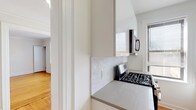 Montclair Gardens D10 is a well-appointed single-floor residence that combines classic architectural details with modern updates. Warm hardwood floors run throughout the entire unit, lending a cohesive and inviting feel to every room. Crown molding accents the ceilings, adding a touch of timeless elegance to the clean, white-painted walls.

The kitchen has been thoughtfully updated with sleek white cabinetry, grey countertops, a white subway tile backsplash, and a full suite of stainless steel appliances, including a gas range, built-in microwave, dishwasher, and refrigerator. A window over the sink allows for natural light and ventilation.

Multiple well-proportioned rooms offer flexibility for living and sleeping arrangements. Each room benefits from multiple windows dressed with blinds, allowing for ample natural light while maintaining privacy. Radiator heating units are present in the rooms, consistent with classic building construction. Several rooms include closets, providing practical storage.

A clean hallway with recessed lighting connects the rooms efficiently. The bathroom features full white tile surrounds, a soaking tub with shower, and a window for natural ventilation. The overall ambiance of the unit is bright, clean, and functional, making it a comfortable and practical residence at Montclair Gardens.
