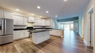 Located at 5478 Deerpath Dr in Sheffield, Ohio, this two-floor home offers a well-designed layout with modern finishes and a cohesive aesthetic throughout. The heart of the main level is an expansive open-concept kitchen, outfitted with crisp white shaker cabinetry, dark granite countertops, stainless steel appliances, and a central island that provides additional prep and gathering space. Light wood-tone luxury vinyl plank flooring runs throughout the main level, complementing the neutral wall tones and recessed lighting overhead. The kitchen flows seamlessly into the living area, which features a ceiling fan and French doors that invite natural light and outdoor views. A full bathroom on the main level features a white vanity with granite countertops and wood-look flooring. Upper-level bedrooms are carpeted for comfort, each equipped with a ceiling fan and windows that bring in natural light. The primary bathroom is a standout, offering a double-sink vanity with granite countertops, wood-look flooring, and a glass-enclosed tile shower with rich dark tile accents. The finished lower level provides generous open space with plush carpeting and recessed lighting, ideal for a recreation room or flexible living area. This home combines functional design with quality finishes at every turn.