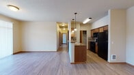 Located at 15720 East 4th Avenue in Spokane Valley, WA, this single-floor unit offers a well-organized and functional layout throughout. The open-concept living and kitchen area serves as the heart of the space, where light wood-style flooring extends across the main living zone, creating a bright and cohesive feel. The kitchen is equipped with warm medium-toned wood cabinetry, tile backsplash, dark granite-style countertops, and black appliances including a refrigerator, range, and built-in microwave. A peninsula with pendant lighting provides additional prep space and naturally defines the transition between the kitchen and living area. A dedicated pantry closet offers generous storage. The hallway leads to the bedroom areas, which feature plush carpeting and windows that invite natural light. One bedroom includes a baseboard heater and a view of the surrounding neighborhood. The bathroom is appointed with a wood-vanity featuring dark hardware and granite-style countertops, a tub-shower combination, and wood-style flooring. Throughout the unit, warm neutral wall tones and wood-accented doors and trim contribute to a cohesive and inviting atmosphere, making this a well-appointed and practical living space.