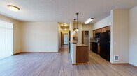Located at 15720 East 4th Avenue in Spokane Valley, WA, this single-floor unit offers a well-organized and functional layout throughout. The open-concept living and kitchen area serves as the heart of the space, where light wood-style flooring extends across the main living zone, creating a bright and cohesive feel. The kitchen is equipped with warm medium-toned wood cabinetry, tile backsplash, dark granite-style countertops, and black appliances including a refrigerator, range, and built-in microwave. A peninsula with pendant lighting provides additional prep space and naturally defines the transition between the kitchen and living area. A dedicated pantry closet offers generous storage. The hallway leads to the bedroom areas, which feature plush carpeting and windows that invite natural light. One bedroom includes a baseboard heater and a view of the surrounding neighborhood. The bathroom is appointed with a wood-vanity featuring dark hardware and granite-style countertops, a tub-shower combination, and wood-style flooring. Throughout the unit, warm neutral wall tones and wood-accented doors and trim contribute to a cohesive and inviting atmosphere, making this a well-appointed and practical living space.