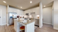 This well-appointed 2-bedroom, 2-bathroom single-floor residence offers a thoughtfully designed open-concept layout with modern finishes throughout. The kitchen serves as a centerpiece of the living space, featuring crisp white cabinetry, granite countertops, a decorative tile backsplash, stainless steel appliances — including a French door refrigerator, range, microwave, and dishwasher — and a spacious island with bar seating, ideal for casual dining or entertaining. The kitchen flows seamlessly into the living room, which benefits from abundant natural light through large windows and a glass door that opens to an outdoor area. A ceiling fan adds comfort to the bright and airy living space. Wood-style plank flooring runs consistently throughout the unit, lending a clean, cohesive aesthetic. Both bathrooms are finished with white vanity cabinetry, granite countertops, large mirrors, and modern fixtures. The primary bathroom offers a double-sink vanity and a walk-in shower. Each bedroom is generously sized, featuring large windows with outdoor views and ceiling fans. The two walk-in closets provide multi-rod hanging systems and shelving. Recessed lighting throughout and a neutral color palette enhance the overall modern, bright ambiance of this well-designed home.