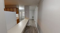 Located at 425 Opelika Rd in Auburn, Alabama, this two-bedroom, two-bathroom unit offers a functional single-floor layout designed for efficient everyday living. The open living and dining area features durable wood-look flooring and neutral gray walls, creating a clean, modern feel. A built-in breakfast bar connects the living space to the galley-style kitchen, which is equipped with wood-toned cabinetry, a white refrigerator, and an electric range with ample counter space for meal preparation. Both bedrooms are carpeted for comfort and feature natural light from windows with blinds. The spacious primary bedroom includes two closets, providing generous storage. The second bedroom is bright and well-proportioned, with natural light filtering in. Both bathrooms are finished with wood-look flooring, and one features a full soaking tub with a surrounding surround. Textured ceilings run throughout the unit, adding a classic touch to the overall aesthetic. The layout is practical and straightforward, making efficient use of the available space throughout. This unit is well-suited for individuals or small households seeking a comfortable, move-in-ready home in Auburn, AL.