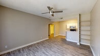 This single-floor unit offers a practical and well-designed layout with consistent wood-look flooring throughout. The open-concept living area is spacious and inviting, featuring a ceiling fan with light, a textured ceiling, and neutral warm-toned walls that create a welcoming ambiance. A large sliding glass door with vertical blinds fills the living space with natural light and provides access to the exterior. The living area flows seamlessly toward the kitchen via an elegant arched passageway, adding a subtle architectural detail to the open floor plan.

The galley-style kitchen is efficiently designed, featuring white shaker cabinetry, light quartz countertops, and a full suite of stainless steel appliances including a refrigerator, electric range, microwave, and dishwasher. A double-basin sink with a modern faucet completes the kitchen setup.

The bedroom is generously sized, with a ceiling fan, a window fitted with blinds that allows natural light to filter in, and a closet with mirrored sliding doors. The full bathroom is clean and functional, equipped with a bathtub and shower combination, a toilet, and a single-sink vanity with a mirrored medicine cabinet above.