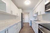 Located at 200 Dennistoun St in Welland, Ontario, this well-appointed two-bedroom, two-bathroom unit offers a thoughtfully designed single-floor layout. Light-toned hardwood-style flooring runs throughout, creating a cohesive and clean aesthetic across all rooms.

The kitchen is a standout feature, showcasing white shaker-style cabinetry with sleek bar-pull hardware, marble-look countertops, a double stainless steel sink with a pull-down faucet, and stainless steel appliances including a refrigerator with freezer drawer. The kitchen connects smoothly to the combined dining and living area, which benefits from large windows that invite generous natural light and views of surrounding greenery.

The primary bedroom is a comfortable, well-proportioned space featuring a large corner window that frames outdoor tree views, baseboard heating, and updated flooring. The second bedroom offers similar finishes, complete with a built-in sliding-door closet and its own window for natural light.

Both bathrooms are finished in a clean, modern style. One features a tub-shower combination with bright white subway tile surround, wood-look flooring, and a vanity with marble-style countertop. The overall ambiance of the unit is bright, neutral, and move-in ready, making it a practical and comfortable home.
