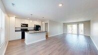Located at 805 E Wheeling St in Lancaster, Ohio, this two-story home offers 2 bedrooms, 3 bathrooms, and a thoughtfully designed layout across two floors. The main living level features an open-concept kitchen and living room area finished with durable wood-look flooring throughout. The kitchen is well-appointed with white cabinetry extending to the ceiling, dark countertops, black appliances including a range, microwave, and refrigerator, and a central island with a double sink and pendant lighting. The spacious living room benefits from large sliding glass doors that invite natural light and provide outdoor views. A full bathroom on this level features wood-look flooring, a vanity with dark countertops, and clean, modern finishes. Upstairs, the primary bedroom is generously sized, featuring soft carpet, a ceiling fan, and a walk-in closet outfitted with wire shelving on multiple walls. The second bedroom also offers carpet flooring, a ceiling fan, and a window with natural light. Two additional closets provide ample storage throughout the home. The attached garage features an automatic opener, concrete flooring, and direct interior access. The home presents a clean, neutral palette with crisp white trim and contemporary finishes throughout.