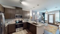 This thoughtfully designed one-bedroom, one-bathroom residence in Houston, TX offers a well-organized single-floor layout that maximizes both comfort and functionality. The open-concept kitchen is a standout feature, showcasing rich dark wood cabinetry, granite countertops, a tile backsplash, and a full suite of stainless steel appliances including a French door refrigerator, electric range, and built-in microwave. Pendant lighting illuminates the kitchen island, which includes an undermount sink and provides additional seating and prep space. Hardwood-style flooring flows throughout the main living areas, adding warmth and visual continuity. The living room is bright and welcoming, benefiting from large windows dressed with floor-length drapes that allow ample natural light. A ceiling fan keeps the space comfortable year-round. The bedroom offers a calm retreat, featuring plush carpet, a ceiling fan, and a large mirror that enhances the sense of space. A bold accent wall adds a distinctive design touch. The bathroom is clean and modern, with dark wood cabinetry, granite countertops, and hardwood-style flooring that echo the design language found throughout the home. Overall, the unit presents a cohesive, contemporary aesthetic suited for comfortable urban living.