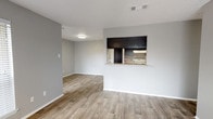 This single-story home offers three bedrooms and two bathrooms within a well-organized floor plan designed for comfortable everyday living. Consistent wood-look flooring runs throughout the main living areas and bedrooms, providing a cohesive and easy-to-maintain finish. Neutral gray walls create a clean, versatile backdrop across all rooms.

The living room serves as the central gathering space, highlighted by a tile-surround fireplace and large windows that allow natural light to filter in. A sliding glass door provides access to an outdoor area. The kitchen connects to the living and dining areas via a pass-through window with a serving ledge, adding openness to the layout. Inside, the kitchen features dark cabinetry, a white electric range, a range hood, and light-toned countertops.

The bedrooms are well-proportioned, with at least one room featuring a ceiling fan with light fixture and a window overlooking greenery. Both bathrooms offer functional fixtures, including a tub-shower combination with white tile surround, a vanity with a granite-style countertop, and a framed mirror. Textured ceilings are present throughout, adding a traditional finish to the overall design.