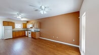 This two-story townhouse in New Orleans, Louisiana offers a practical and comfortable layout across two floors. The main level features an open living and kitchen area with warm hardwood flooring throughout. The kitchen is well-appointed with ample honey-toned wood cabinetry, dark granite-style countertops, a tile backsplash, and white appliances including a refrigerator, electric range, microwave, and dishwasher. A ceiling fan overhead keeps the living area comfortable, while warm earth-toned walls add a welcoming character to the space. A convenient half-bathroom on the main level features tile flooring, a wood vanity with a single sink, and a mirror with overhead lighting. Also on the main floor is an in-unit laundry closet housing a stacked washer and dryer. Upstairs, the two bedrooms are carpeted and bathed in natural light from windows with blinds. The primary bedroom includes a ceiling fan and access to additional spaces, while a carpeted hallway with closet storage connects the upper-level rooms. The full bathroom features a wood vanity with ample cabinet storage. This townhouse provides a functional, move-in-ready living experience in a convenient New Orleans location.