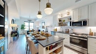 Located at 770 Juniper St NE in Atlanta's vibrant Midtown neighborhood, this thoughtfully designed single-floor residence combines contemporary style with functional living. The open-concept kitchen and living area form the heart of the home, anchored by a striking kitchen island with a dark stone countertop, built-in shelving, and seating for multiple guests. White shaker cabinetry with gold hardware, a classic subway tile backsplash, and a full suite of stainless steel appliances lend the kitchen a clean, polished aesthetic. Statement brass pendant lights hang overhead, adding warmth and character to the space. The living area flows seamlessly from the kitchen, featuring light hardwood floors, generous natural light from large windows, and sweeping views of the Atlanta skyline. Two well-proportioned bedrooms each offer large windows framing city views and access to a private balcony, creating bright and airy retreats. The bathroom is finished with a navy double-vanity accented by gold hardware, white countertops, light tile flooring, and an illuminated mirror, delivering a spa-inspired feel. Throughout the residence, a refined design palette of crisp whites, warm metallics, and rich accent tones creates a cohesive and inviting atmosphere.