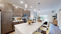 Located on Good Hope Road in Menomonee Falls, WI, this well-appointed 1-bedroom, 1-bathroom residence offers a thoughtfully designed single-level layout. The open-concept kitchen and living area serves as the heart of the home, anchored by a sleek white quartz island with seating, rich dark wood cabinetry, stainless steel appliances, and stylish pendant lighting overhead. Light wood-tone flooring flows throughout, enhancing the bright, airy atmosphere. The living room is generously sized, bathed in natural light through a large sliding glass door that opens to a private balcony with outdoor views, making it ideal for relaxing or entertaining. The spacious primary bedroom features plush carpeting, a large window overlooking greenery, and ample room for furnishings. A dedicated office nook provides a quiet workspace, while the full bathroom is finished with wood-toned cabinetry, a white quartz vanity top, and wood-look flooring. A closet offers practical storage. Clean white walls and recessed lighting throughout lend the space a modern, cohesive feel, making this a comfortable and functional residence in a convenient Menomonee Falls location.