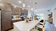 Located on Good Hope Road in Menomonee Falls, WI, this well-appointed 1-bedroom, 1-bathroom residence offers a thoughtfully designed single-level layout. The open-concept kitchen and living area serves as the heart of the home, anchored by a sleek white quartz island with seating, rich dark wood cabinetry, stainless steel appliances, and stylish pendant lighting overhead. Light wood-tone flooring flows throughout, enhancing the bright, airy atmosphere. The living room is generously sized, bathed in natural light through a large sliding glass door that opens to a private balcony with outdoor views, making it ideal for relaxing or entertaining. The spacious primary bedroom features plush carpeting, a large window overlooking greenery, and ample room for furnishings. A dedicated office nook provides a quiet workspace, while the full bathroom is finished with wood-toned cabinetry, a white quartz vanity top, and wood-look flooring. A closet offers practical storage. Clean white walls and recessed lighting throughout lend the space a modern, cohesive feel, making this a comfortable and functional residence in a convenient Menomonee Falls location.