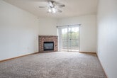 Located at 915 Ellis Ave in Baraboo, Wisconsin, this single-floor, 2-bedroom, 2-bathroom residence offers a well-designed layout with a comfortable and functional living environment. The open-concept kitchen and living room serve as the heart of the home, where a peninsula breakfast bar with pendant lighting separates the kitchen from the carpeted living area. The kitchen features warm honey-toned cabinetry, light countertops, tile-style flooring, and black appliances including a refrigerator, range, and microwave. The spacious living room is highlighted by a classic brick fireplace, a ceiling fan, and sliding glass doors that open to a private patio, allowing natural light to fill the space. Both bedrooms are generously sized, carpeted, and feature arched windows that frame views of the surrounding greenery, along with individual climate control units. The primary bedroom is notably spacious, offering ample room for furnishings. Storage is a standout feature of this residence, with seven closets throughout — including walk-in closets equipped with wire shelving systems. The two bathrooms are finished with tile-style flooring, warm wood vanities, and full tub-shower combinations. Clean white walls and consistent warm wood trim create a cohesive, neutral aesthetic throughout.