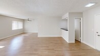 Located at 6000 Buckingham Pkwy in Culver City, California, this single-floor residence offers a clean, contemporary design with a bright and airy atmosphere throughout. The open-concept living and dining area features warm wood-tone flooring, neutral gray walls, and large sliding glass doors fitted with vertical blinds that allow generous natural light to pour in. A ceiling fan adds practical comfort to the living space, while a built-in bar-height counter provides a seamless transition to the kitchen area. The kitchen is well-appointed with white shaker-style cabinetry, white quartz countertops, a stainless steel electric range, and wood-tone flooring, creating a fresh and functional cooking environment. The bedrooms feature plush carpeting, large windows with vertical blinds, and sliding closet doors, offering a quiet and comfortable retreat. The bathrooms are thoughtfully designed — one features a tub-shower combination enclosed by frosted sliding glass doors alongside a vanity with white cabinetry, while another offers a dual-sink vanity with gray countertops, white cabinetry, and direct access to a walk-in closet. Textured ceilings are consistent throughout, and the overall neutral color palette provides a versatile, move-in-ready canvas.