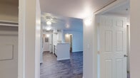 Located at 1295 Grand Summit Drive in Reno, Nevada, this single-floor unit offers a clean, modern interior with a thoughtfully designed open layout. The main living area features durable wood-style plank flooring and a ceiling fan, creating a comfortable, well-ventilated space. A door with a full-length sidelight panel opens to an outdoor area, allowing natural light to fill the room.

The kitchen is anchored by a central peninsula with white cabinetry and light countertops, providing both prep space and a natural dividing point between the kitchen and living areas. Black appliances — including a refrigerator, electric range with overhead exhaust hood — complement the crisp white cabinetry.

The bedrooms are carpeted for warmth and comfort, with windows fitted with blinds that offer views of the surrounding greenery. Closet space is accessible directly from the bedroom areas. Two bathrooms serve the unit: one features a tub-shower combination with white tile surround, a vanity with under-sink storage, and wood-style flooring; the other includes an overhead cabinet, mirror, and matching finishes.

A dedicated laundry area houses a full-sized washer and dryer alongside an electrical panel. The unit's neutral color palette and consistent finishes throughout contribute to a bright, move-in-ready atmosphere.