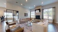 Located at 7125 Sea Breeze Dr W in Sunbury, Ohio, this thoughtfully designed single-floor space offers a refined blend of modern aesthetics and functional layout. The grand entry welcomes visitors with a striking black-and-white checkered tile floor, soaring ceilings, and floor-to-ceiling arched windows that flood the space with natural light, creating an open and airy first impression. A bold, dark accent wall adds dramatic contrast, setting the tone for the interior's sophisticated design language. The spacious living area features elevated ceilings, rich hardwood-style flooring, and a floor-to-ceiling stone-clad fireplace serving as a commanding focal point. Neutral-toned furnishings, a glass coffee table, and curated wall art contribute to the room's contemporary yet inviting ambiance. Large windows allow abundant natural light to pour in, with views of the surrounding greenery. The kitchen is well-equipped with crisp white shaker-style cabinetry, dark countertops, a subway tile backsplash, stainless steel appliances, and a central island that offers additional workspace and seating. The overall design throughout the space maintains a cohesive palette of cool grays, whites, and natural wood tones, delivering a polished and professionally appointed environment ideal for both gathering and productivity.