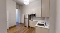 Located at 740 N Plankinton Ave in the heart of Milwaukee, WI, this efficiently designed one-bedroom, one-bathroom unit offers a thoughtfully laid-out single-floor living space. Warm hardwood-style flooring runs continuously throughout, creating a cohesive and inviting atmosphere from room to room.

The kitchen is outfitted with light wood cabinetry providing ample storage, white countertops, a stainless steel refrigerator, an over-the-range microwave, a cooktop, and a single-basin sink — delivering a clean, modern aesthetic well-suited for everyday living.

The bedroom is a cozy, well-defined space featuring neutral walls, the same warm flooring, and a built-in closet with an overhead storage shelf and hanging rod, offering practical organization solutions.

The bathroom is clean and functional, appointed with a full soaking tub and shower combination featuring built-in shelving, a toilet, and a light wood vanity with a white countertop and sink. A mirrored medicine cabinet provides additional storage, completing the room's efficient design.

Throughout the unit, a neutral color palette of whites and soft grays, paired with warm flooring tones, lends the space a modern yet approachable character — ideal for urban living in downtown Milwaukee.