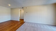 This single-floor residence offers a practical and comfortable layout designed for everyday living. The entryway welcomes you with warm hardwood-style flooring that extends throughout the main living and kitchen areas, creating a cohesive and inviting atmosphere.

The kitchen is well-equipped with warm wood cabinetry, light countertops, stainless steel appliances including a range and refrigerator, and a stylish mosaic tile backsplash that adds a decorative touch. Ample cabinet storage and a functional layout make it a practical space for cooking and meal preparation.

The living area is generously sized, featuring plush carpeting, a textured ceiling, and a ceiling fan with a light fixture for added comfort. A large sliding glass door with vertical blinds fills the room with natural light and provides access to the outdoors.

The bedrooms are carpeted and comfortable, each featuring ceiling fans, windows with blinds for natural light and privacy, and access to closet storage. The transition between rooms is highlighted by a mix of hardwood-style and carpeted flooring, adding visual interest throughout.

The bathroom is clean and functional, outfitted with a full tub and shower combination with chrome fixtures, a dark wood vanity with a light countertop, and hardwood-style flooring that ties the space together neatly.