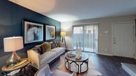 Located in Houston's Briarwest neighborhood, this thoughtfully designed single-story residence offers a cohesive and stylish interior with carefully curated details throughout. The living area serves as a striking focal point, featuring a deep teal accent wall adorned with large-framed artwork, dark hardwood-style flooring, and a sliding glass door that invites natural light and outdoor access. Adjacent to the living space, the dining area continues the bold teal accent wall theme, illuminated by a contemporary ceiling fixture and accented with decorative metallic wall art. The galley-style kitchen is efficiently laid out with white cabinetry, dark granite-style countertops, black appliances including a range and refrigerator, and a double basin sink — all tied together with hardwood-style flooring. The bedrooms offer comfortable, carpeted retreats, each with ceiling fans, window treatments for privacy, and ample space. One bedroom features a walk-in closet, while another showcases a tray ceiling detail. The bathrooms are clean and well-finished, with white vanity cabinetry, granite-style countertops, and a tub-shower combination. Throughout the home, a neutral gray palette paired with bold teal accents and warm wood tones creates a modern yet inviting ambiance.
